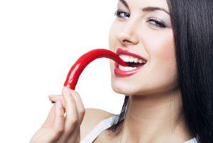 A beautiful woman eating a hot pepper