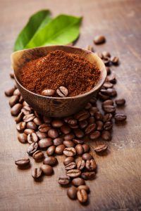 Wooden Bowl with ground coffee on wooden table