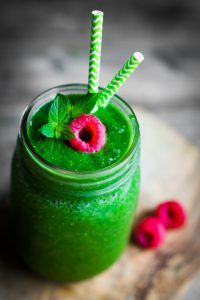 Fresh green smoothie on rustic wooden background