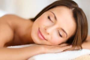 beautiful woman with closed eyes in spa salon lying on the massage desk