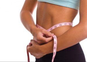 a slim woman measuring her waist