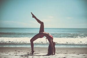 a woman doing yoga on the beach
