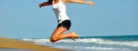 a happy woman jumping on the beach