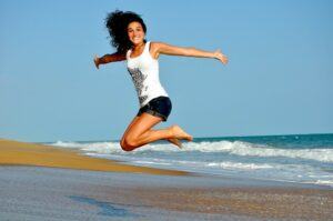 a happy woman jumping on the beach